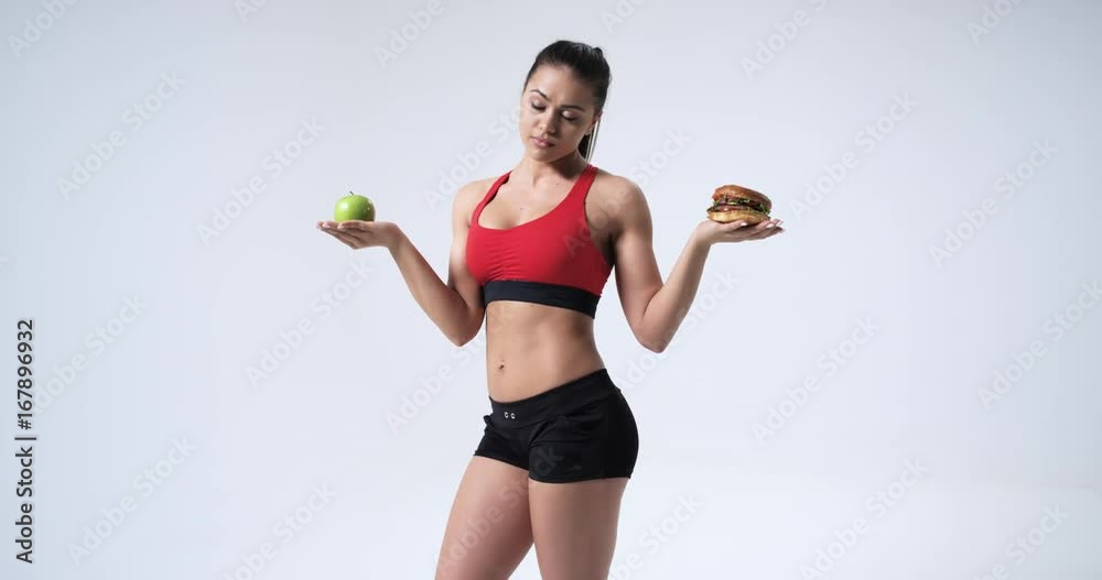 Athlete woman choosing between apple and hamburger, in slow motion. Red Epic. 4k Athlete woman choosing between apple and hamburger, in slow motion. Red Epic. 4k