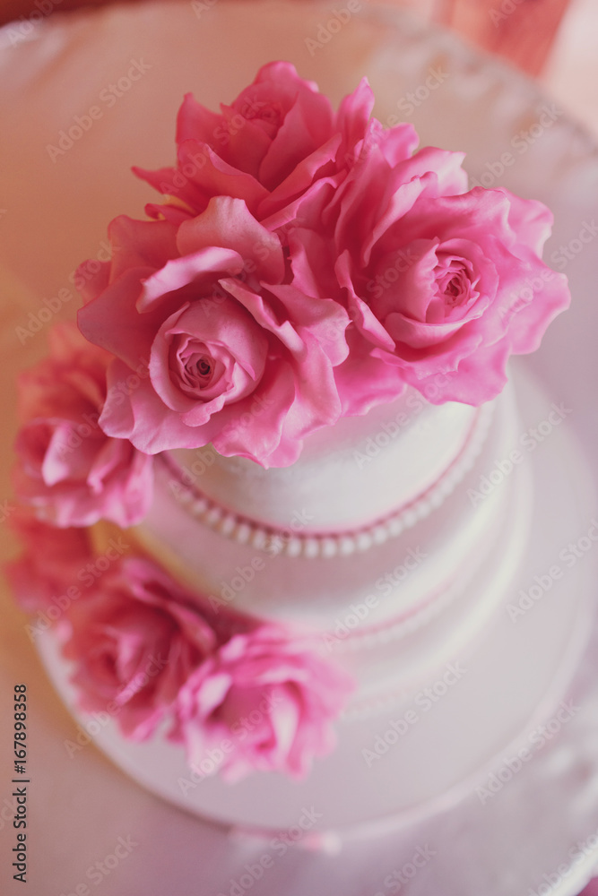 Wedding cake covered with white icing and decorated with pink roses Wedding cake covered with white icing and decorated with pink roses