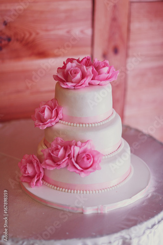 Wedding cake covered with white icing and decorated with pink roses