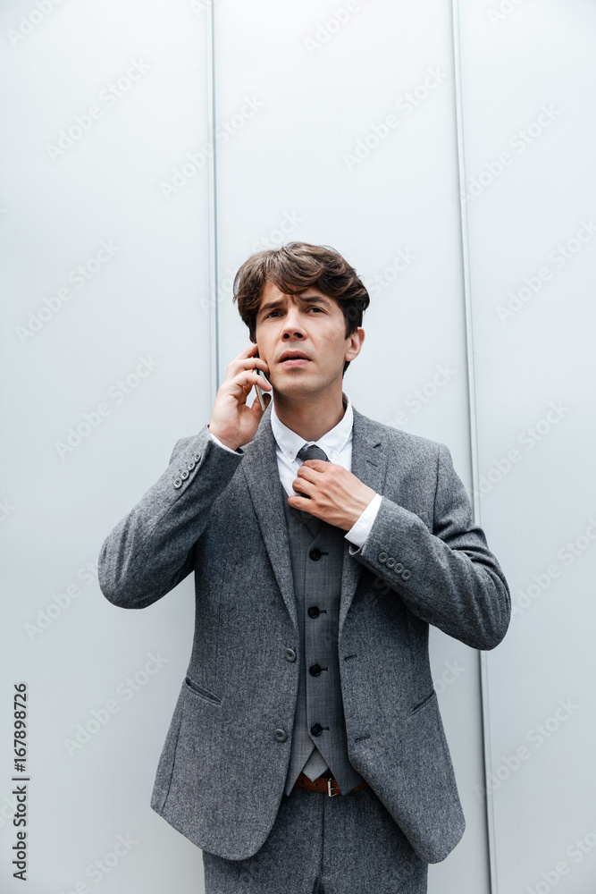 Handsome businessman in suit standing and talking on mobile phone Handsome businessman in suit standing and talking on mobile phone