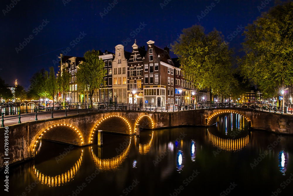 Night shot of the city, many bicycles on the bridge on Amsterdam canal, Netherlands