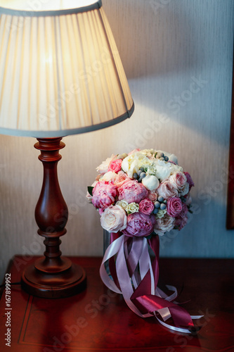 Pink wedding bouquet stands under the lamp