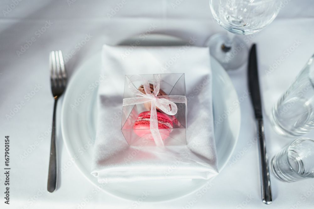 Box with macaroons put on a white napking on dinner plate Box with macaroons put on a white napking on dinner plate