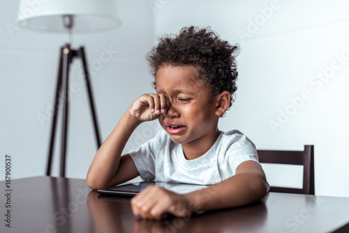 Canvas-taulu boy crying while sitting with tablet