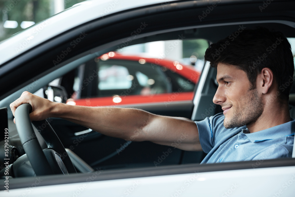 Happy smiling male customer testing his new car