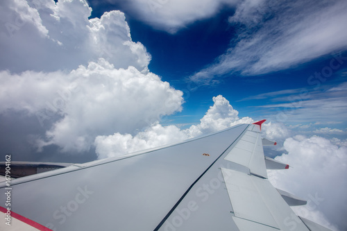 Wing of airplane  clouds and blue sky  view from the window of airplane. 