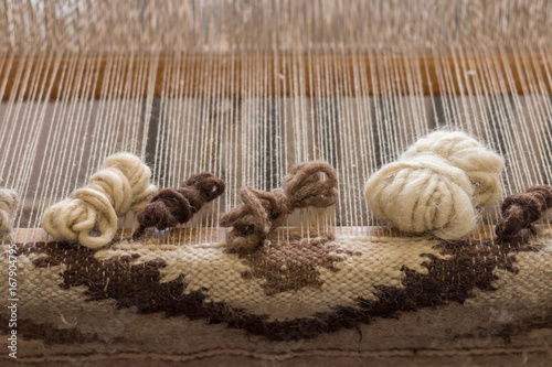 Ukrainian wooden handloom creating a handwoven woollen fabric / carpet