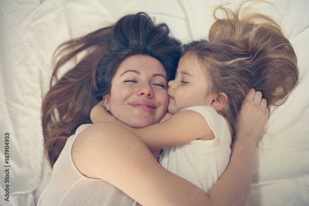 Young mother playing with her little daughter on bed. Enjoy together in free time. Young mother playing with her little daughter on bed. Enjoy together in free time.
