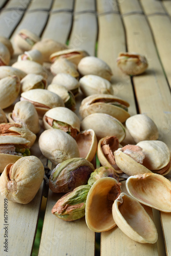Pistachio nuts on bamboo table. Vertical image.