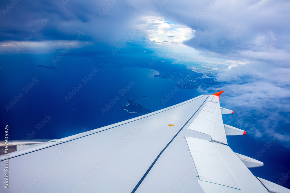 Obraz premium Wing of airplane, clouds and blue sky, view from the window of airplane. 