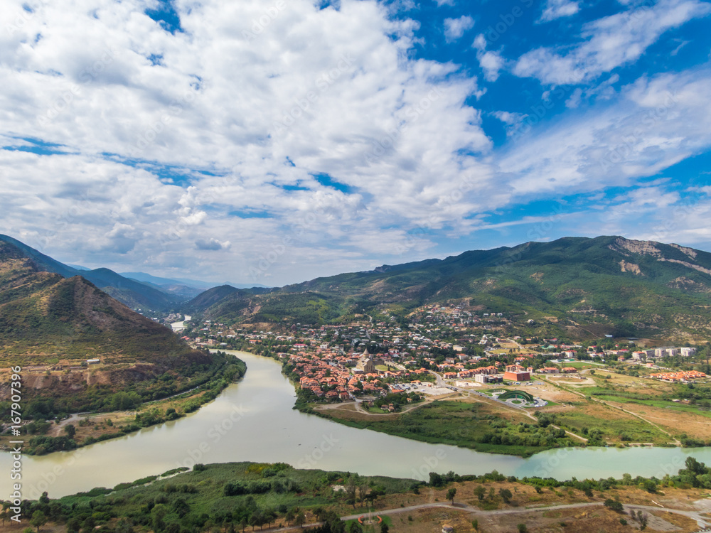 Naklejka premium The Top View Of Mtskheta, Georgia, The Old Town Lies At The Confluence Of The Rivers Mtkvari And Aragvi. Svetitskhoveli Cathedral, Ancient Georgian Orthodox Church, Unesco Heritage In The Center.