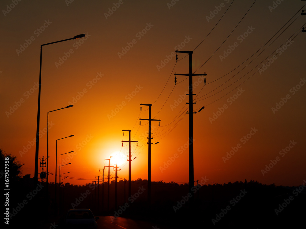 road with power line and lamp posts in sunset