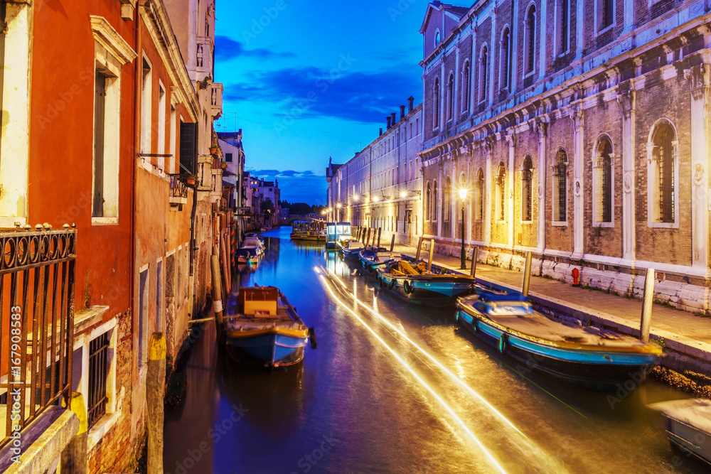Night long exposure photo of Venice with typical Venetian buildings and boats.