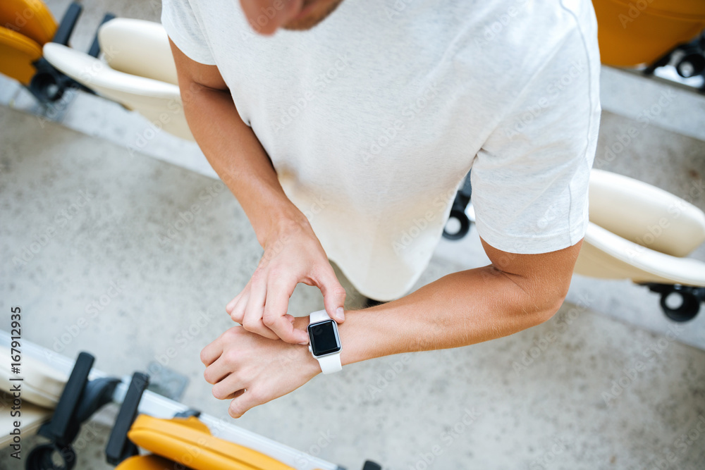 Cropped photo of young sports man looking at watch