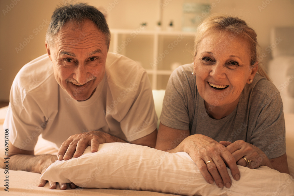 Senior couple lying together in bed and looking at camera. Senior couple lying together in bed and looking at camera.