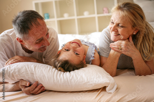 Grandmother and grandfather lie together with their granddaughter. © liderina