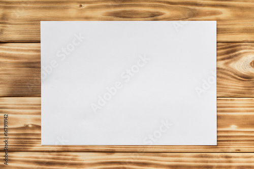 Mockup of white a4 paper list at textured wooden table background.