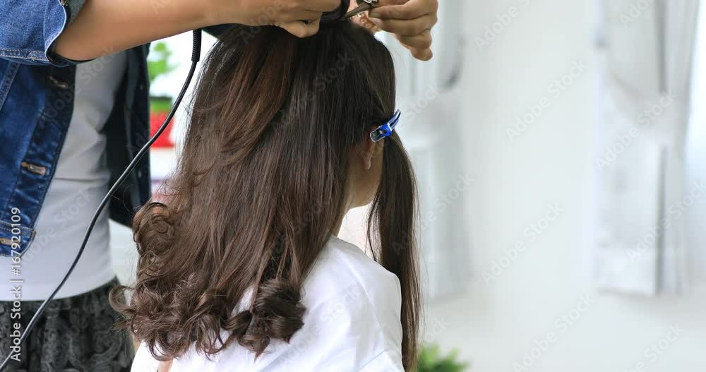 Female hairdresser standing and making hairstyle to cute lovely young asian teen in beauty salon Female hairdresser standing and making hairstyle to cute lovely young asian teen in beauty salon