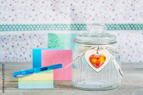 Glass Jar with Lid Near Pastel Notes Stack with Blue Pen on Top