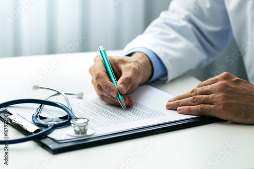 doctor writing documents at desk in clinics office