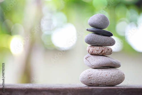 Balance Stones stacked to pyramid in the soft nature green background.