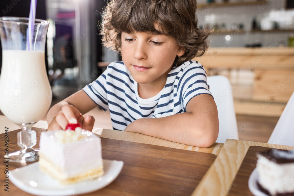 cute little boy with piece of cake in cafe cute little boy with piece of cake in cafe