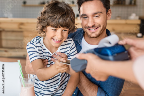 happy son and father paying with credit card in cafe photo