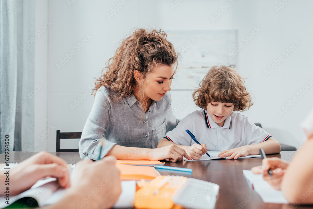 mother and beaautiful curly son doing homework together mother and beaautiful curly son doing homework together