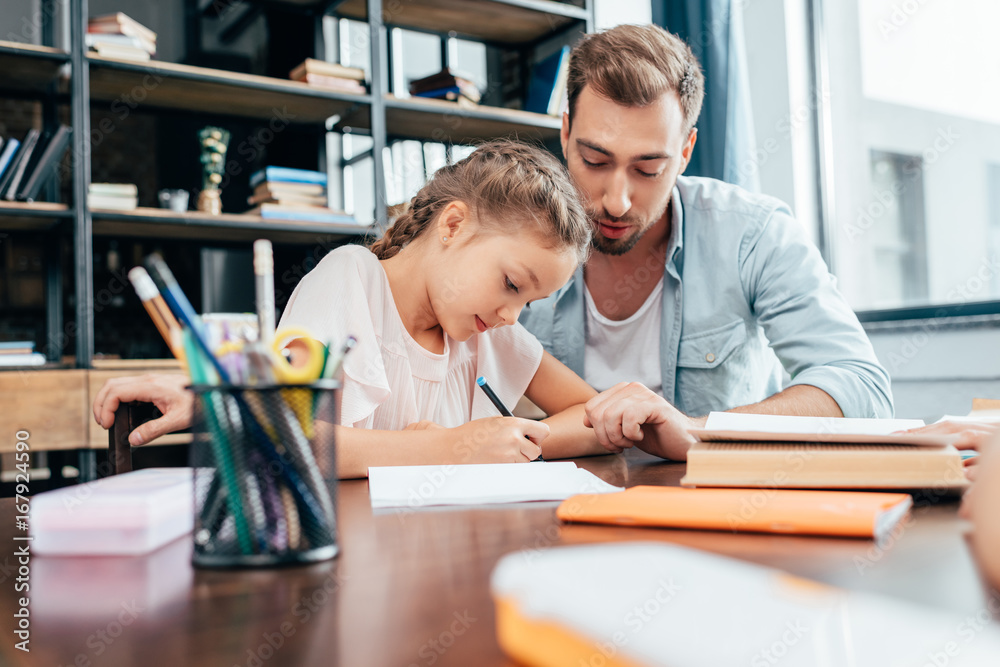 young father doing homework with little daughter young father doing homework with little daughter