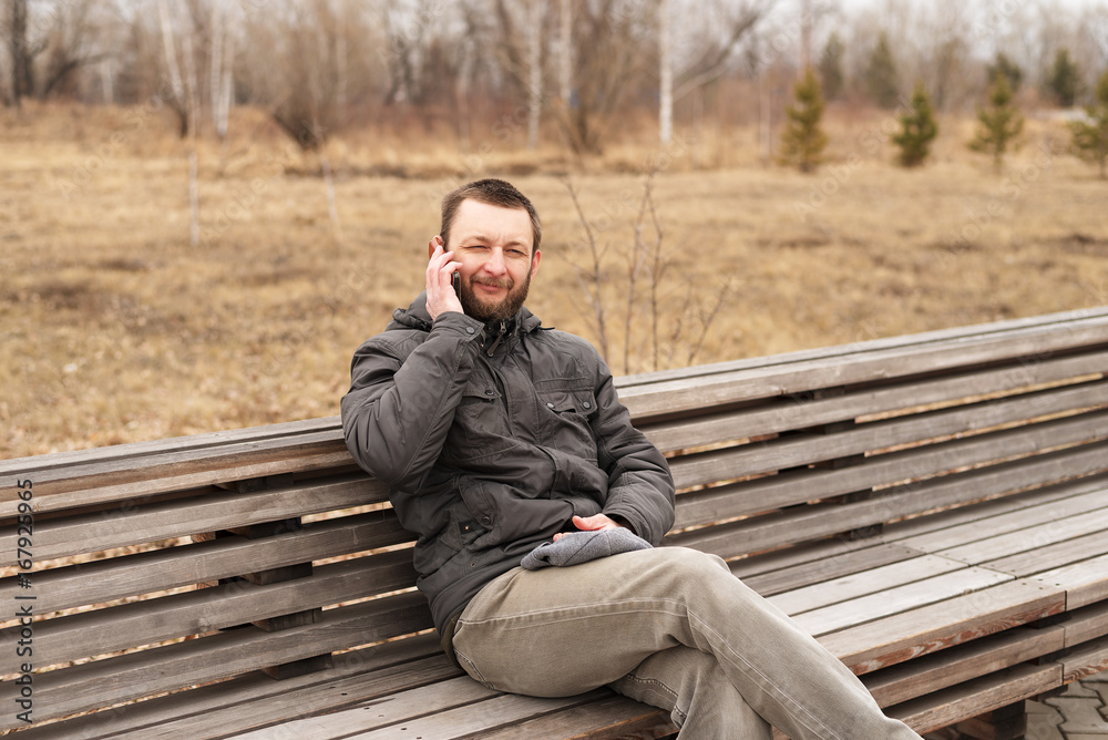 Fototapeta premium Young man talking on a smartphone outdoors