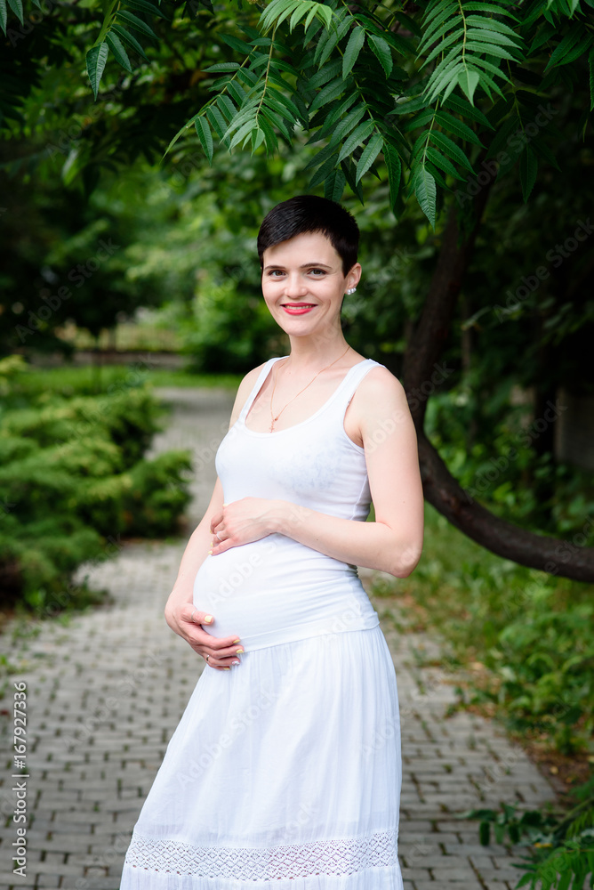 Beautiful pregnant girl in a white dress outdoors. Beautiful pregnant girl in a white dress outdoors.