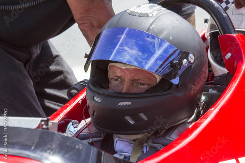 Man in IRL race car with helmet photo