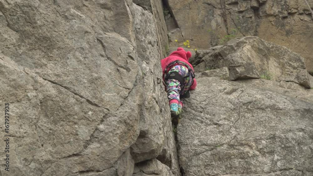 Little girl climber is practicing climbing on a vertical rock Little girl climber is practicing climbing on a vertical rock