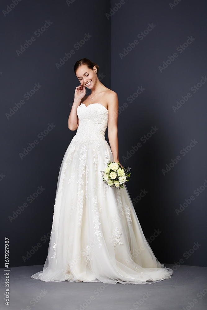 Beautiful bride smiling in white wedding dress, studio