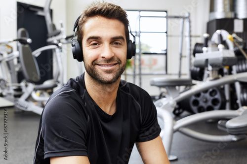 Headphones guy in portrait and smiling in gym