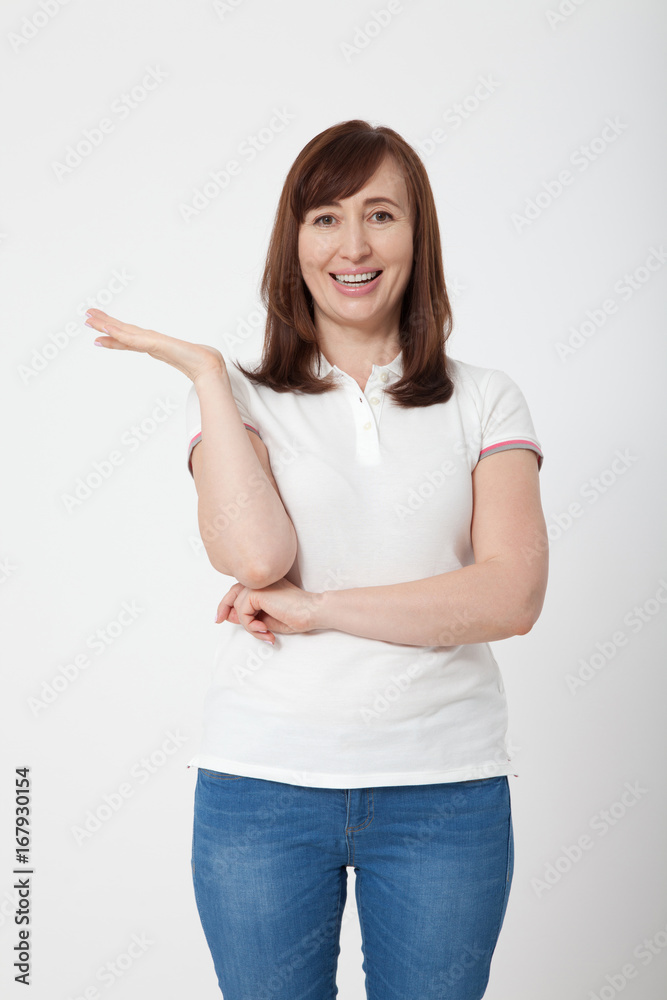 Middle age woman showing copy space isolated on white background. Smiling brunette female. T shirt. Middle age woman showing copy space isolated on white background. Smiling brunette female. T shirt.