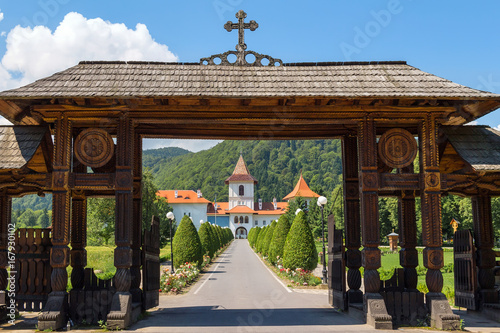 Wooden entrance gate and road to Brancoveanu monastery in Sambata de Sus village, Romania photo