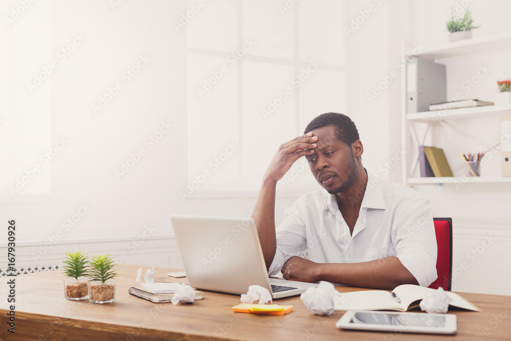 Tired black businessman in office, work with laptop