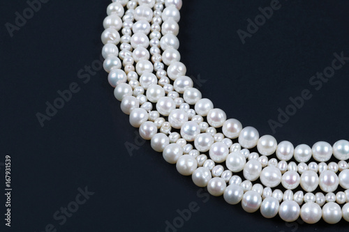 White pearl necklace on the dark background