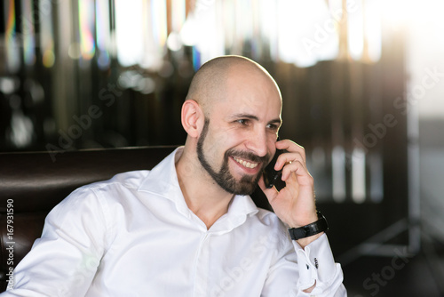 A brutal bald man talking on the phone. © fotofrol