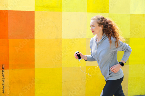 Side view of woman running against bright wall photo