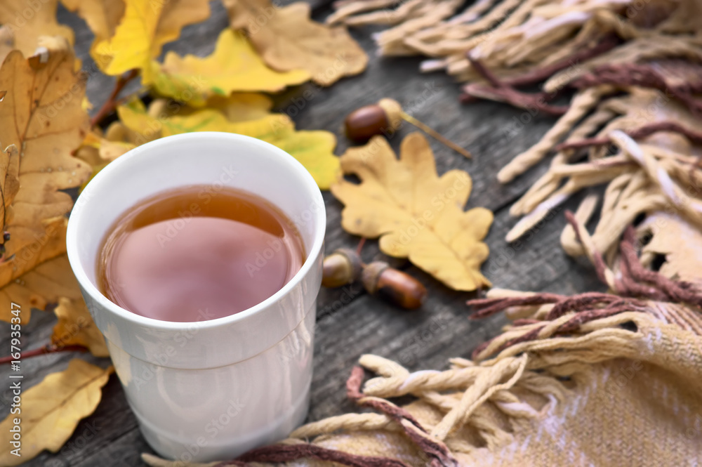 Cup of tea on a wooden background, plaid in autumn, yellow and red leaves