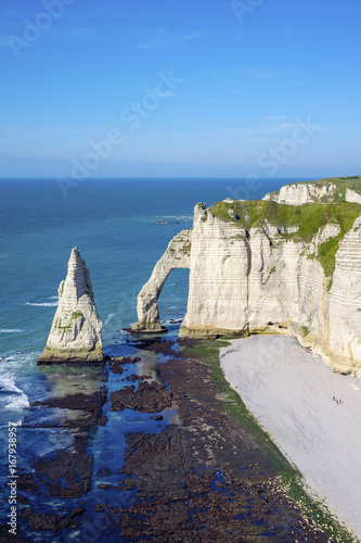 France, Normandy (Normandie), Seine-Maritime department, Etretat. White chalk cliffs and Aiguille d'Etretat, natural stone arch on the coast. photo