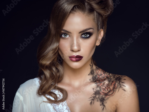 Close up portrait of beautiful model with artistic make up and hairstyle. Floral body art on her shoulder. Ideal woman concept. One half symbolizes a good housewife, another one – a passionate lover