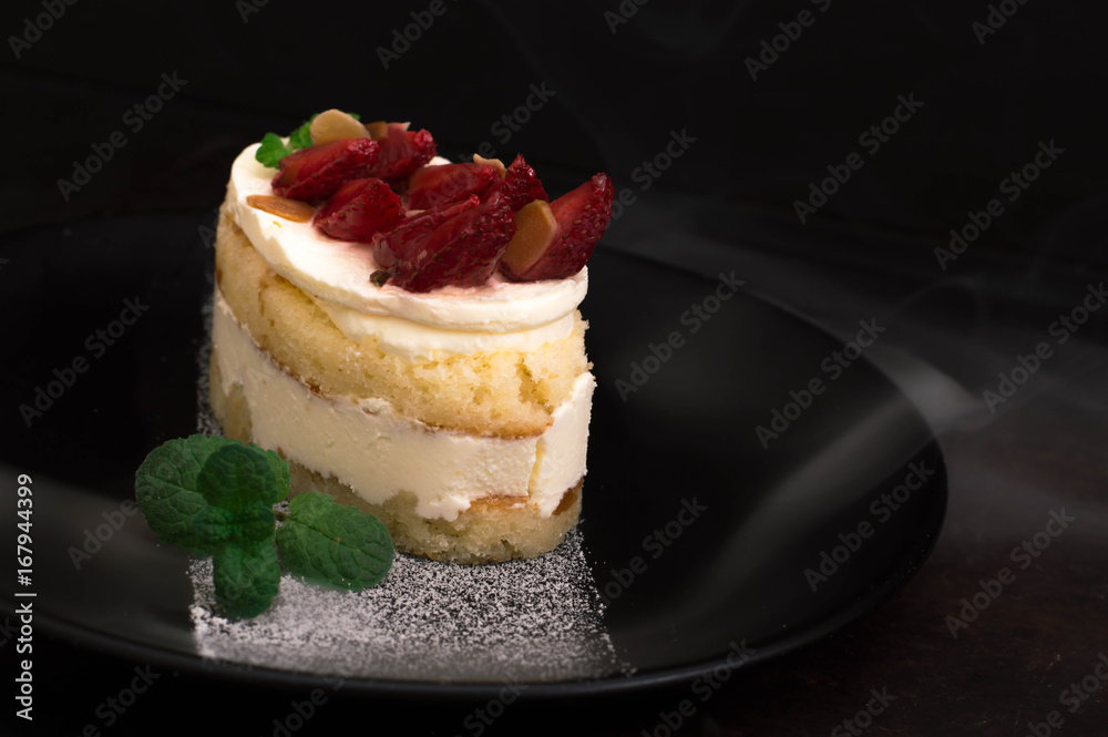 Strawberry cake with almond petals. Old black background. Close-up. Top view