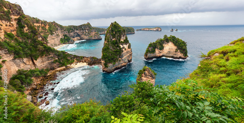 Sea coast view with little house standing on the high cliff bring above sea and little rocky islets. Atun beach, Nusa Penida island. Popular travel destination on Bali holidays. Indonesian background.