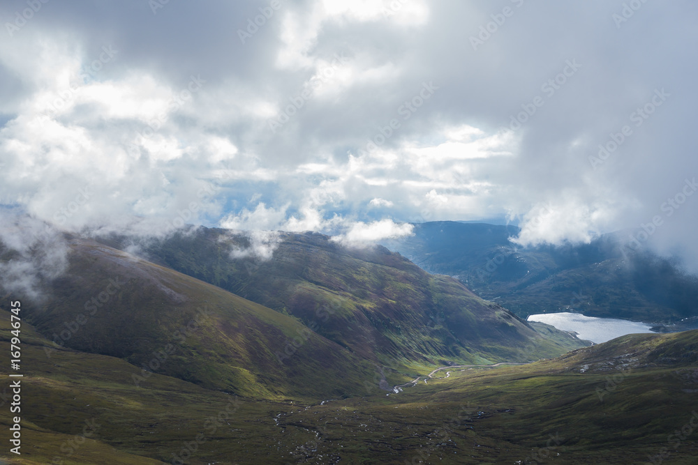 Fototapeta premium River descending Scottish Highland mountain valley to lake under clouds