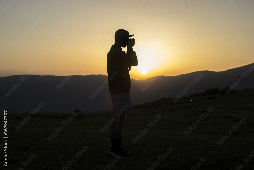 Silhouette of man which taking photo in the mountians