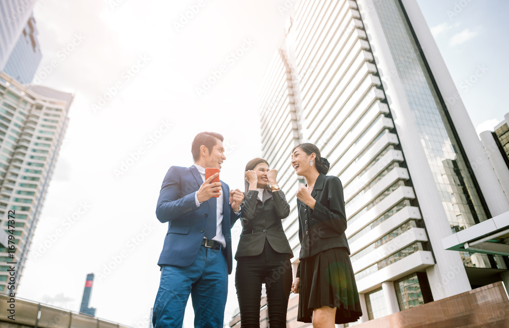 Celebrating success. Low angle view of excited young businessman and business woman keeping arms raised and expressing positive while standing outdoors with office building in the background Celebrating success. Low angle view of excited young businessman and business woman keeping arms raised and expressing positive while standing outdoors with office building in the background