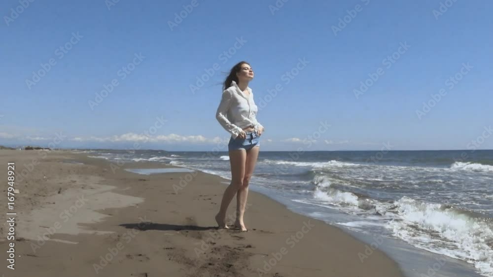 Beautiful young teen woman with blowing hair arms raised, brunette running on beach enjoying life, slow motion. Beautiful young teen woman with blowing hair arms raised, brunette running on beach enjoying life, slow motion.